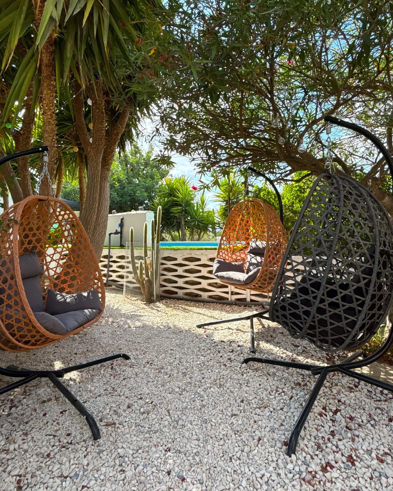 Sillones colgantes de ratán en la zona chill junto a la piscina