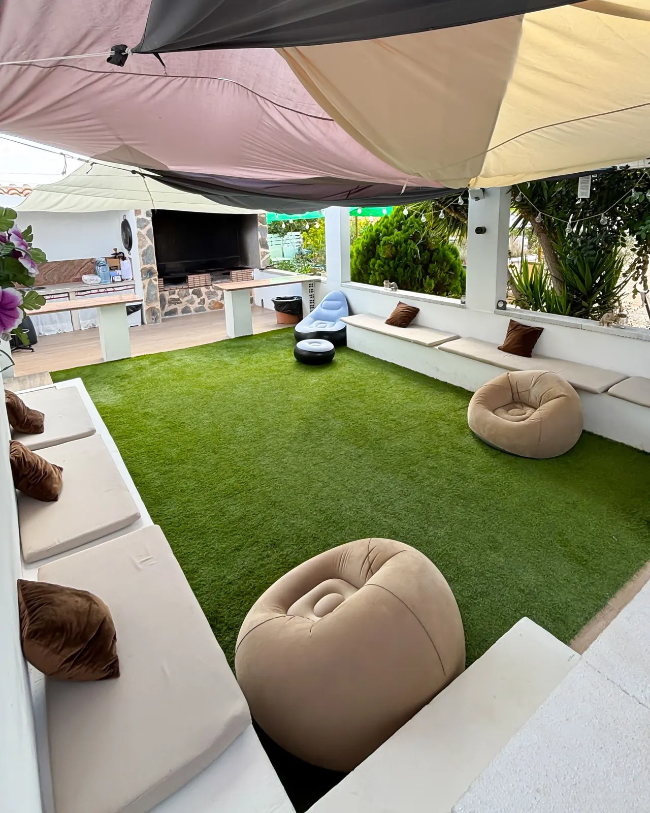 Rincón chill out con sofás bajos y flores junto a la zona de barbacoa