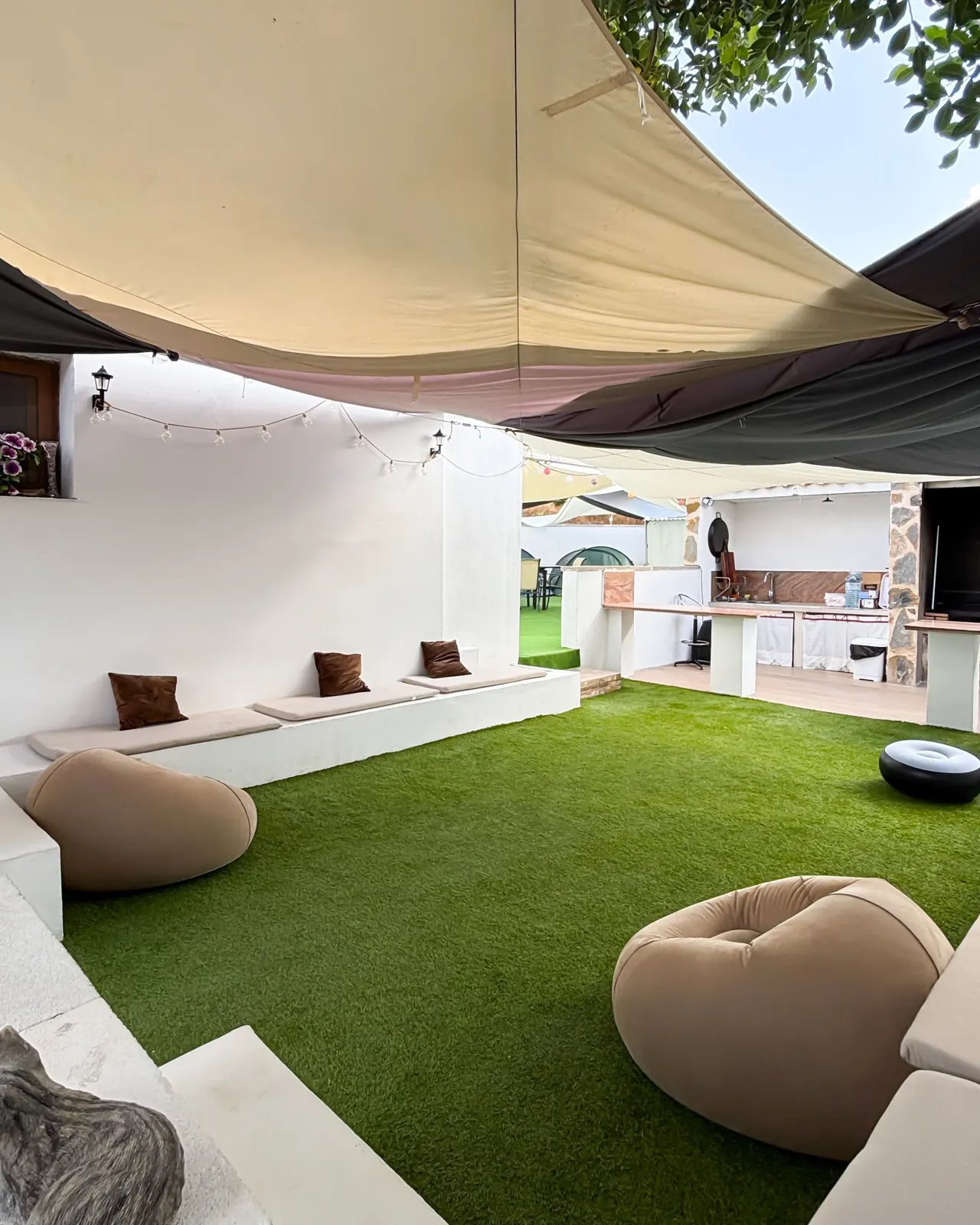 Sofás de obra con cojines y luces de guirnalda en la zona relax