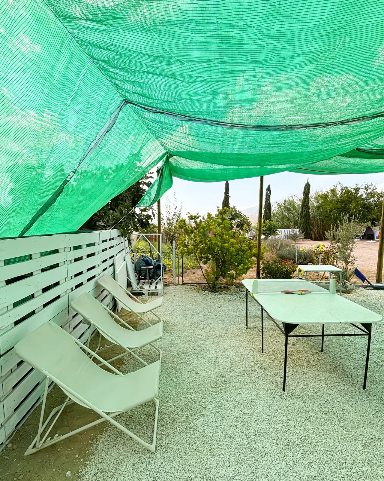 Tumbonas y mesa de ping-pong bajo malla de sombra