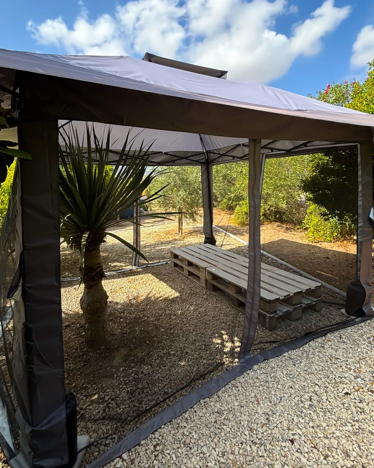 Carpa exterior con banco de madera en la zona ajardinada